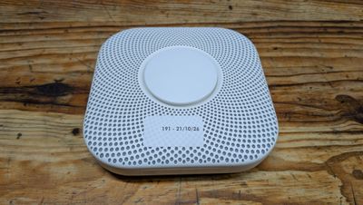 un gros plan d'un détecteur de fumée blanc posé sur une table en bois