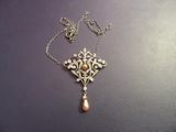 un collier en argent avec un pendentif en perle et une chaîne, posé sur une table