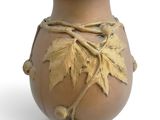 un vase marron orné de feuilles sur fond blanc