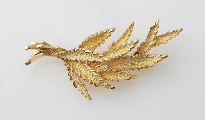 an image of a gold leaf brooch on a white surface