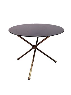a round glass table with gold legs and a black top