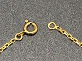 two pieces of gold chain on a gray surface