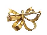 an image of a gold bow brooch on a white background
