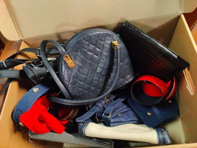 une boîte remplie de sacs à main et de sacs à bandoulière posée par terre