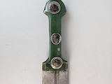 a green and silver knife on a white surface