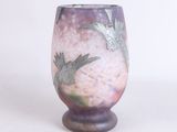 un vase violet orné d'un oiseau, posé sur un fond blanc