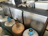 many gas bottles lined up on a shelf in a kitchen