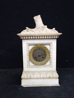 une petite horloge blanche surmontée d'un oiseau