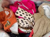un tas de vêtements et un ours en peluche dans un panier
