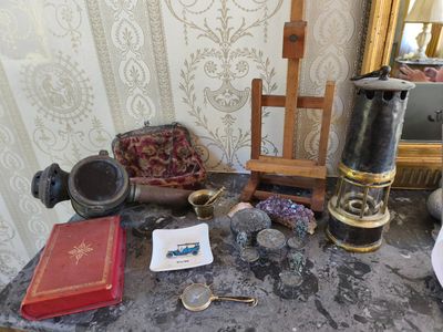 une table sur laquelle se trouvent un miroir, un livre, une lampe et d'autres objets