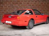a red car parked in front of a brick wall