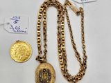 a close up of a gold necklace with a coin on a table