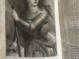 Quelqu'un tient un vieux livre sur lequel figure le dessin d'une femme en armure.
