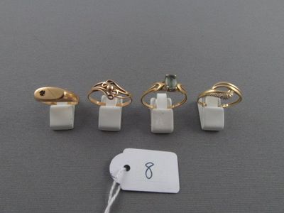 quatre bagues et une étiquette posées sur une table, avec une étiquette de prix