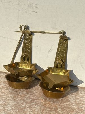 pair of antique brass scales on a table with a white wall in the background