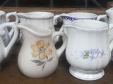 seven vases sitting on a wooden table with flowers painted on them