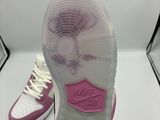 someone is holding a pair of pink and white shoes on a white surface
