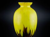 un vase jaune posé sur une surface noire
