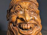 tête en bois sculptée représentant un homme qui rit, posée sur une table
