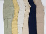 un lot de cinq paires de pantalons posées sur une surface blanche