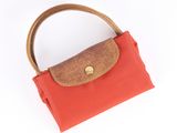 orange and brown purse with wooden handle on white background