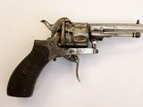 un vieux revolver avec une poignée en bois sur une surface blanche