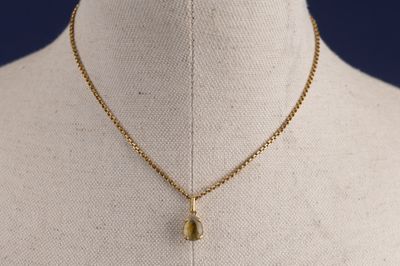 un collier en or avec un pendentif en forme de larme sur un mannequin