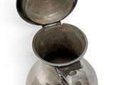 a silver cup with a spoon in it on a white surface