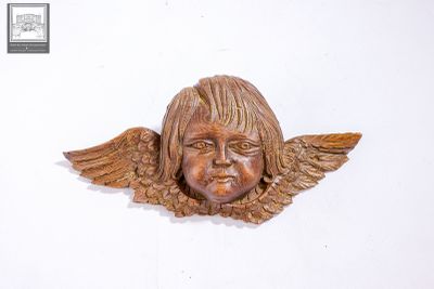 une sculpture en bois représentant un enfant avec des ailes sur la tête