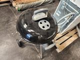 a black grill sitting on top of a wooden pallet