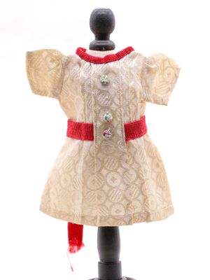 robe beige et rouge sur un mannequin, ornée d'un ruban rouge