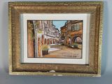 tableau représentant une scène de rue avec des bâtiments et des fleurs, dans un cadre doré