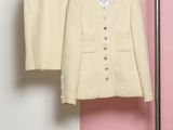 une veste et un pantalon suspendus à un portant devant un mur rose et blanc