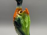 un oiseau en céramique perché sur une plante