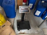 a scale on the floor next to some blue barrels