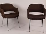 pair of brown chairs sitting next to each other on a white surface