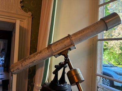 un télescope posé sur un trépied devant une fenêtre