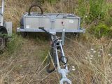 a small trailer with a bike attached to it in the grass