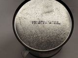 a close up of a metal cup on a white surface