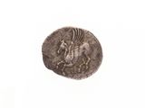 une vieille pièce de monnaie sur laquelle figure un cheval, posée sur une surface blanche