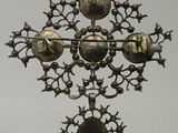 a metal cross hanging on a wall with a clock on it