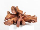 wooden sculpture of a pile of wood sticks on a white pedestal