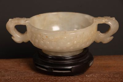 a white bowl on a black stand on a wooden table