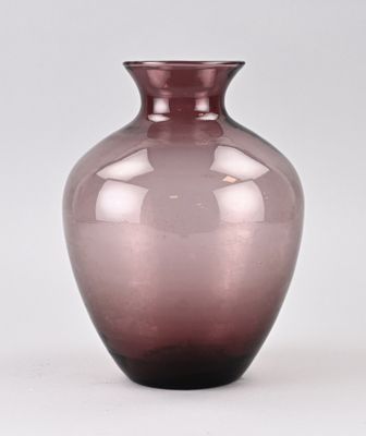 un vase en verre violet posé sur une surface blanche