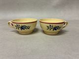 two yellow cups with blue flowers on them sitting on a table