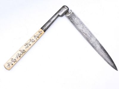 un couteau avec un manche en bois sur une surface blanche