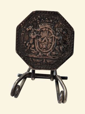 a small metal object with a coat of arms on it