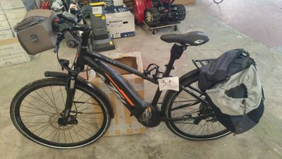 un vélo garé dans un garage, avec un sac à l'arrière