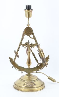 une photo d'une lampe de table en laiton sur laquelle est posé un compas