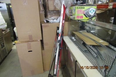 Plusieurs paires de skis et de bâtons de ski sont empilés sur une étagère dans un magasin.